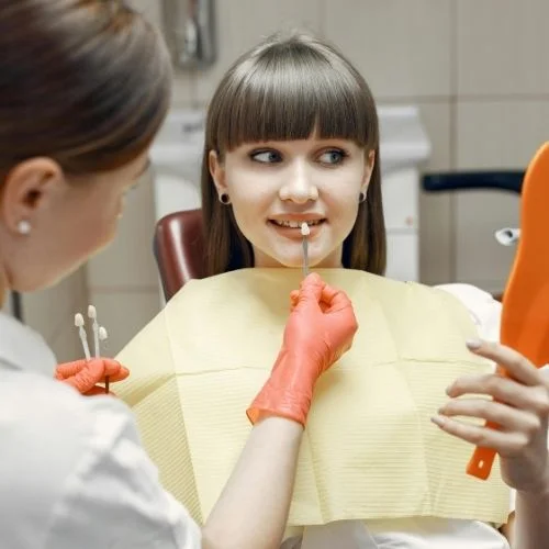 Dentist matching tooth shade for veneers on a young patient at Dental Art Clinic in Cambridge.