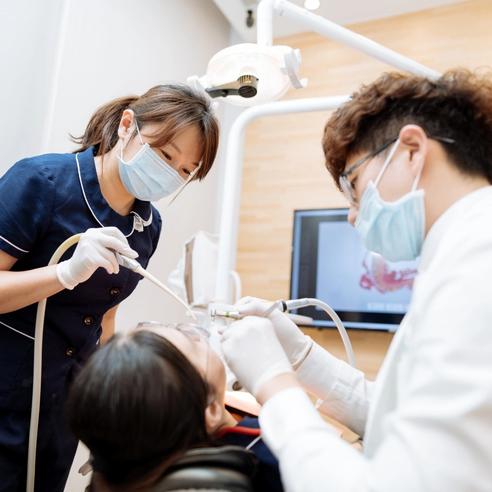 Dentist and assistant performing a dental treatment on a patient at Dental Art Clinic in Cambridge.
