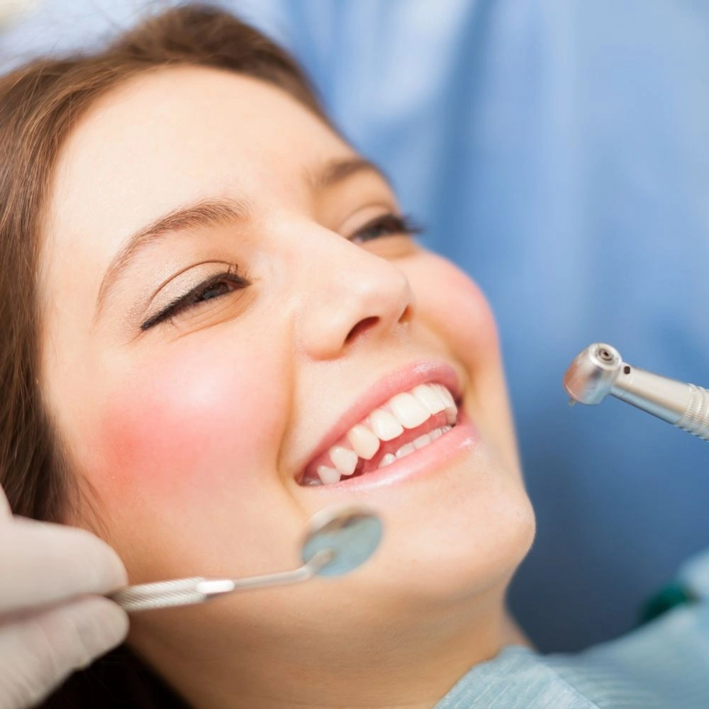 Patient smiling during a routine dental exam with dental instruments at Dental Art Clinic in Cambridge.