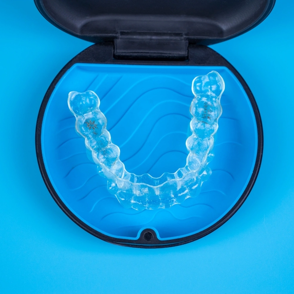 Clear orthodontic aligner in its storage case used for teeth straightening at Dental Art Clinic in Cambridge.