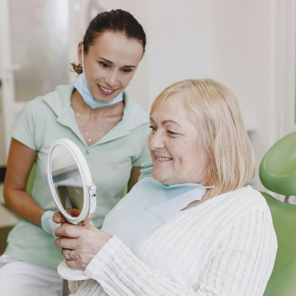 Patient reviewing new dentures in a mirror with the dentist at Dental Art Clinic in Cambridg
