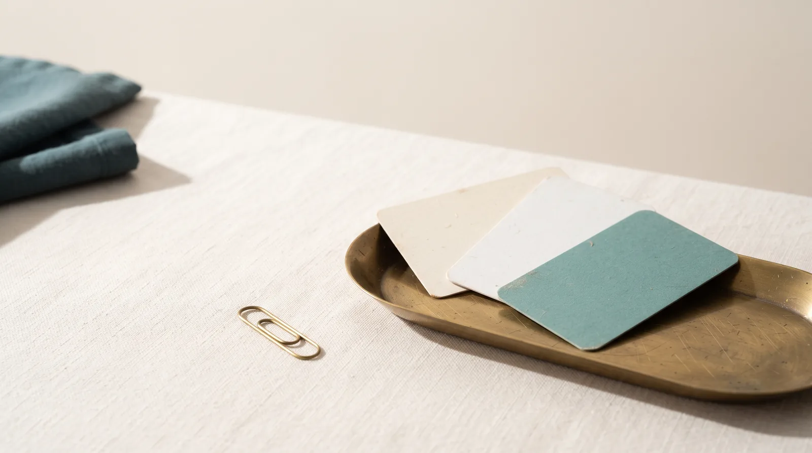 Three blank plain cards fanned in a shallow brass tray on linen
