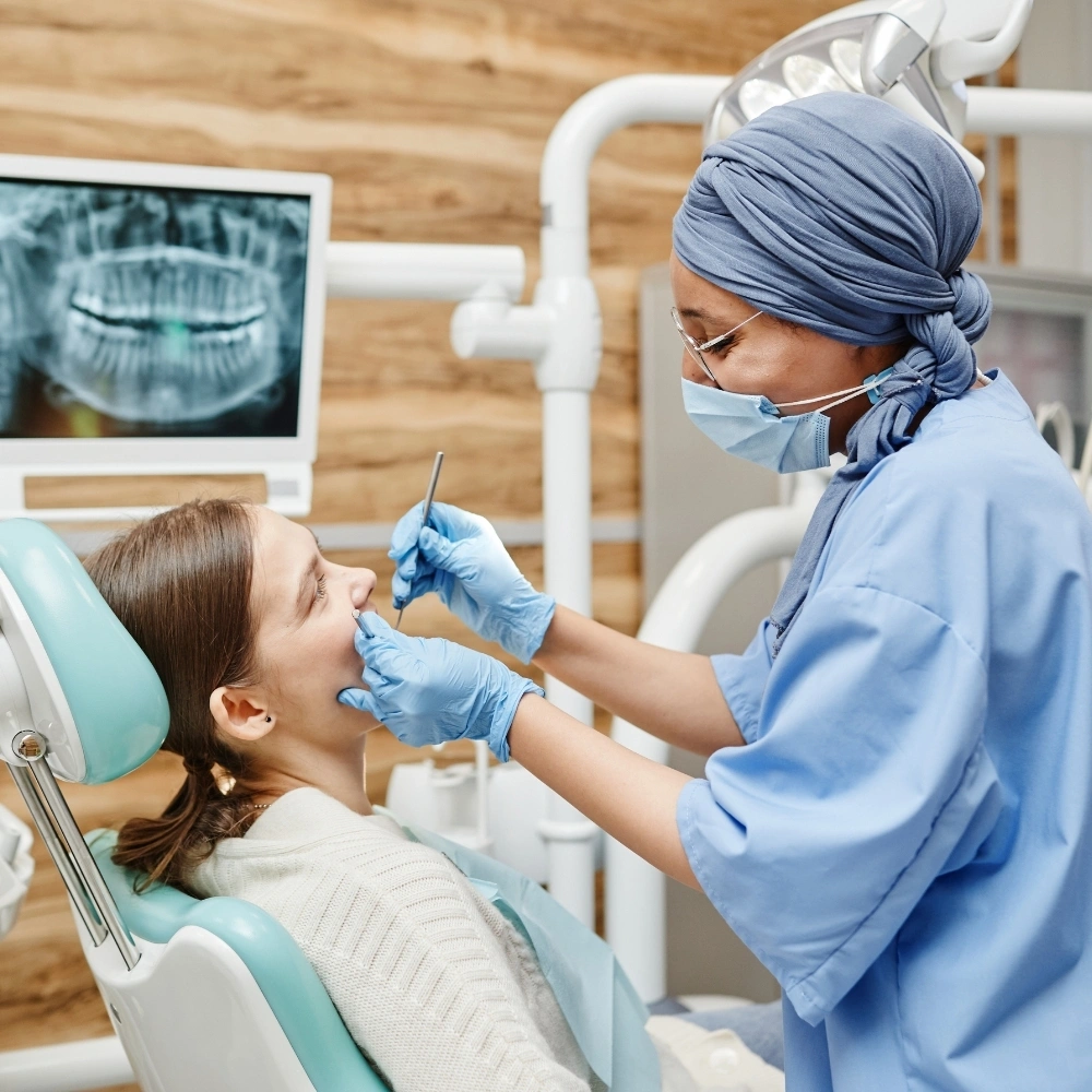 Dentist performing an endodontic evaluation with dental X-ray displayed in the background at Dental Art Clinic in Cambridge.