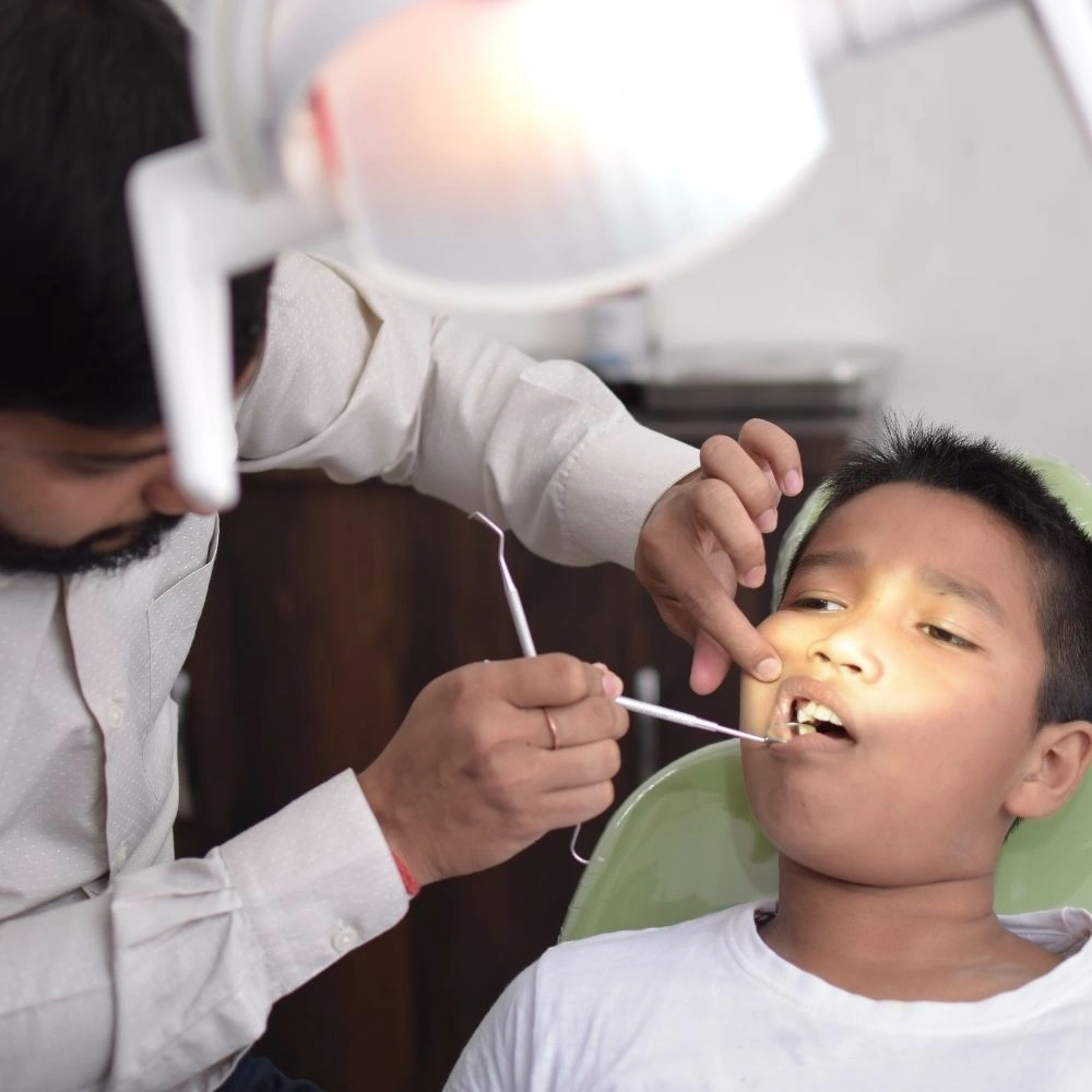 Child receiving a routine dental checkup from a dentist at Dental Art Clinic in Cambridge.