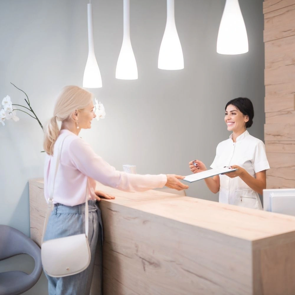 A patient checking in at the front desk of Dental Art Clinic in Cambridge.